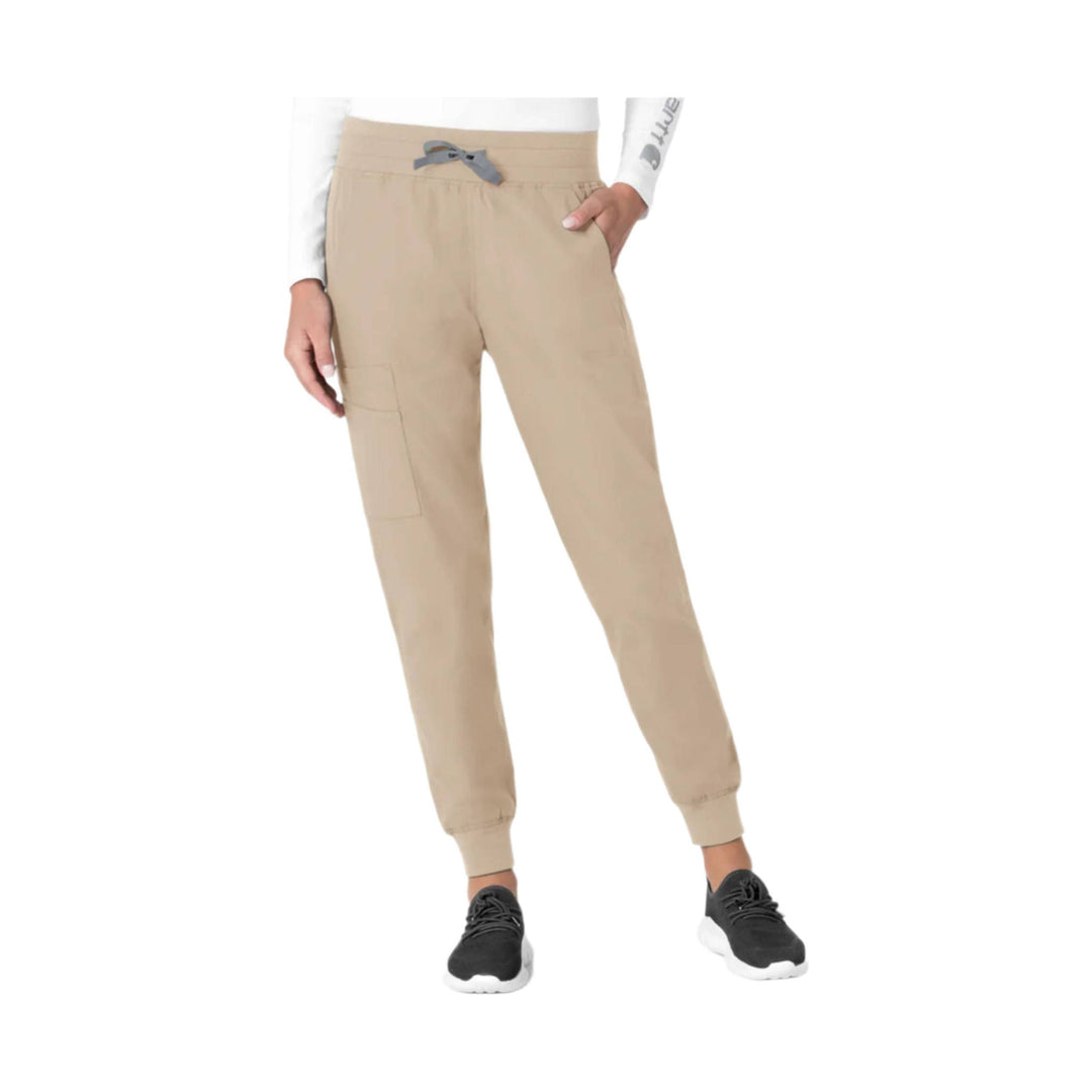 Khaki jogger scrub pants with elastic drawstring waist, cargo pocket, and cuffed ankles, worn with black sneakers