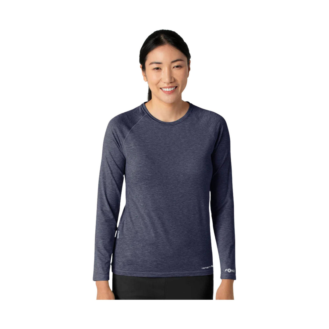 Woman wearing a dark heather long-sleeve crewneck top with small logo text on the sleeve and hem
