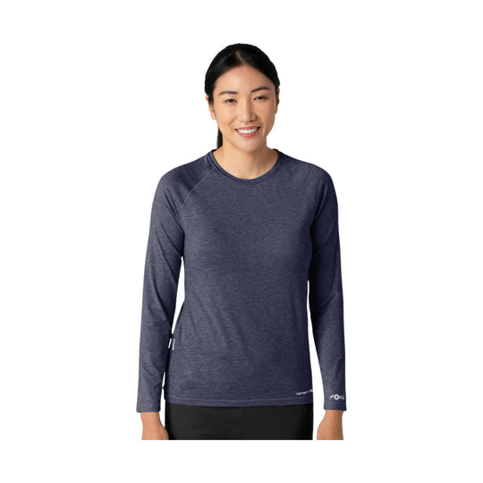 Woman wearing a dark heather long-sleeve crewneck top with small logo text on the sleeve and hem