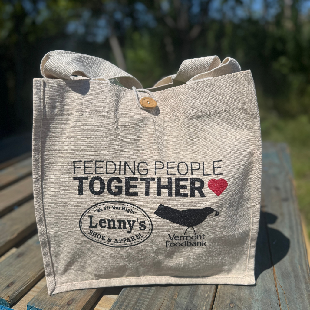 Tote bag with 'Feeding People Together' text and logos on a wooden surface
