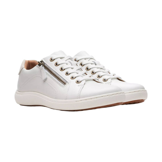 White low-top leather sneakers with side zippers, white laces, and tan lining