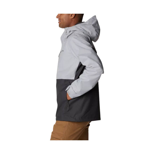 Grey and black hooded rain jacket shown in side profile, with hand in pocket