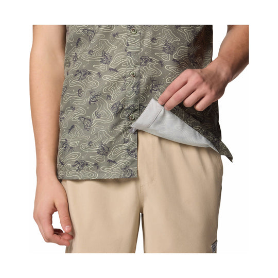 Olive patterned camp shirt with buttons, worn open over beige pants