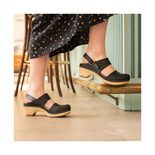 Black closed-toe clog sandal with a wooden wedge heel and ankle strap