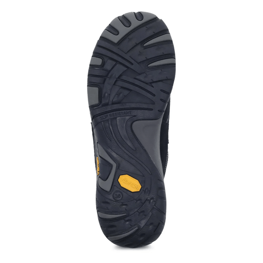 Black rubber shoe outsole with deep tread, slip-resistant marking, and yellow logo insert