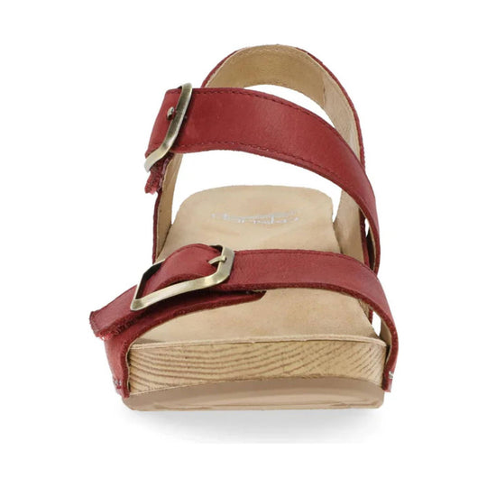 Red leather sandal with two wide straps, metal buckles, and a cork wedge heel