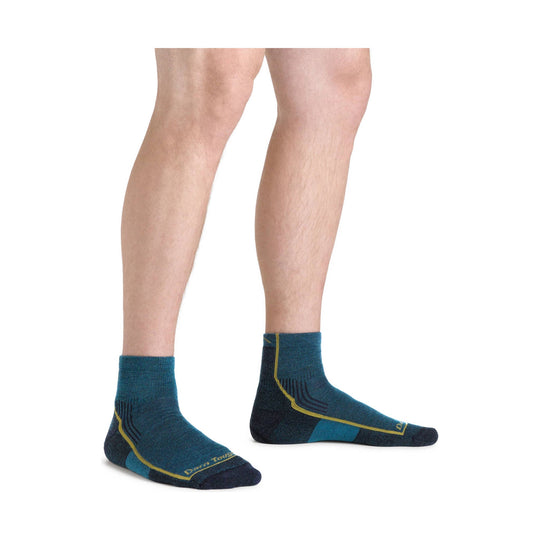 Pair of dark teal ankle hiking socks with navy and yellow accents, worn on a model's lower legs