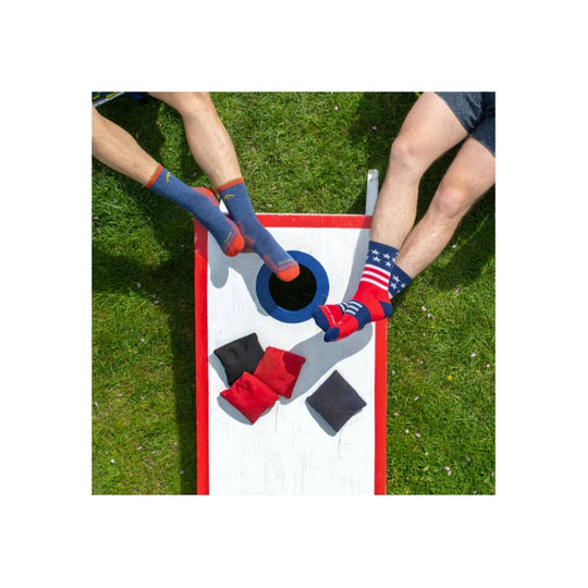 Blue hiking socks with red toes and patriotic stars-and-stripes pattern on a cornhole board