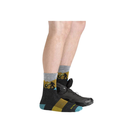 Dark hiking socks with gray cuffs, mustard accents, and turquoise toes, worn with black hiking shoes