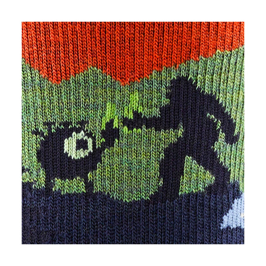 Close-up of a knit hiking sock with orange, green, navy, and black mountain and hiker pattern