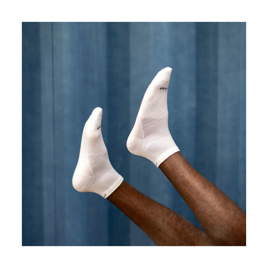 Pair of white quarter running socks on raised legs against a blue backdrop