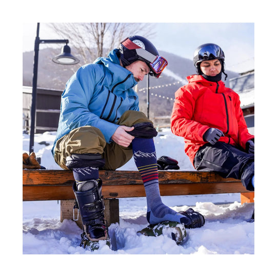 Over-the-calf ski socks with mountain pattern and multicolor stripes worn with ski boots