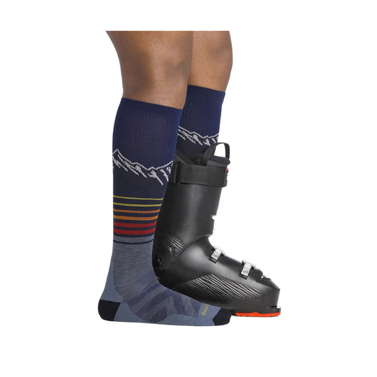 Navy knee-high ski socks with mountain pattern and multicolor stripes, shown with a black ski boot