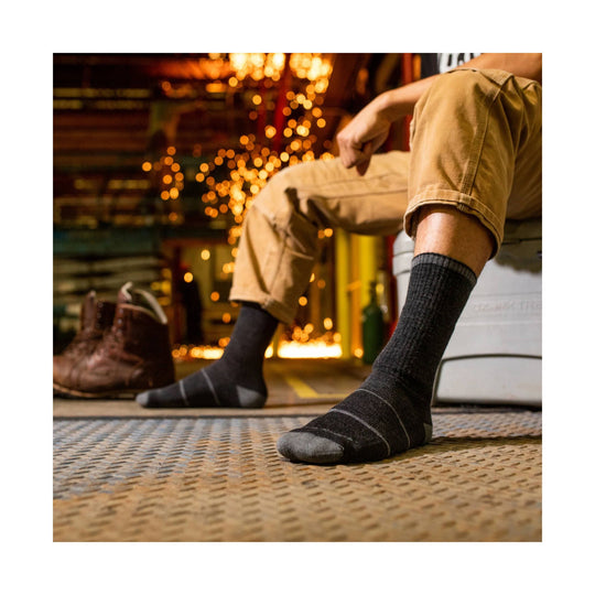 Black ribbed crew socks worn with tan work pants, shown beside brown leather work boots.
