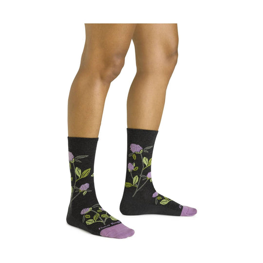 Black crew socks with purple floral and green leaf pattern, shown on a model’s lower legs