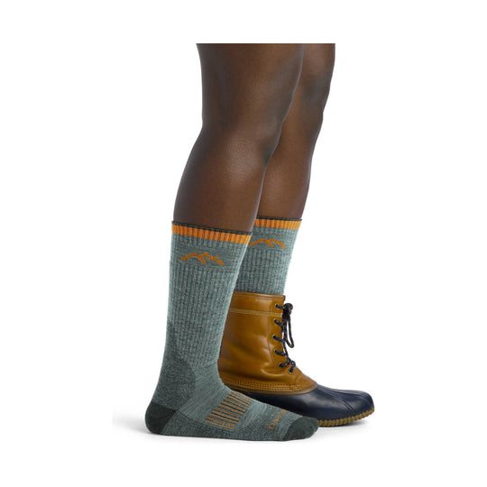 Gray ribbed knee-high hiking socks with orange stripes and mountain logo, shown with brown lace-up boots