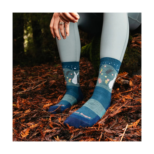 Blue patterned hiking socks worn with light leggings, shown on a person crouching outdoors