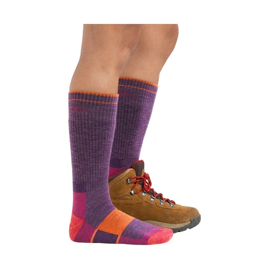 Purple and pink knee-high hiking socks with orange trim worn with tan hiking boots.