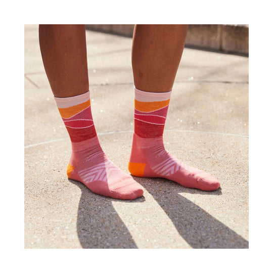 Pink-and-orange patterned running socks worn on a person standing outdoors.