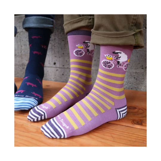 Purple crew socks with yellow stripes and a bicycle-riding sheep graphic, plus a navy sock with pink animal prints