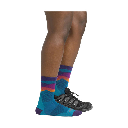 Purple, teal, and orange patterned crew running sock on a model wearing black trail shoes