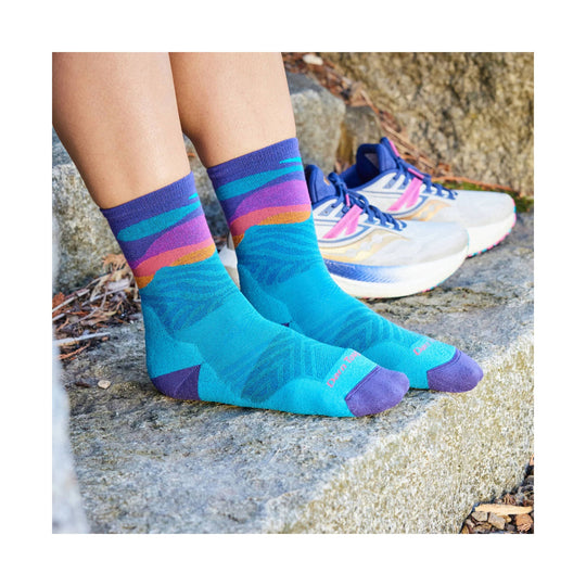 Bright blue ankle socks with purple toes and multicolor striped cuffs, worn with white running shoes