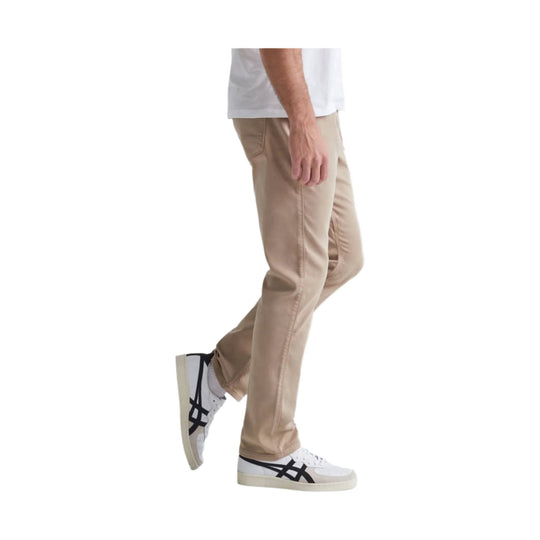 Beige relaxed taper pants worn with white sneakers, side view
