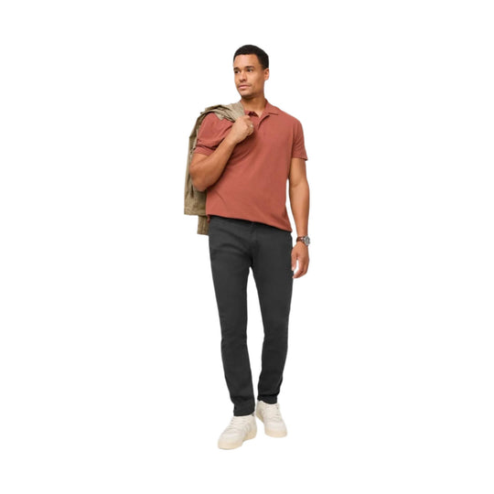 Man wearing black relaxed taper pants with white sneakers and a rust polo shirt