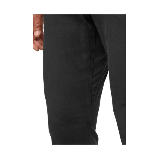 Black tapered pant leg with front seam and a hand at the pocket opening