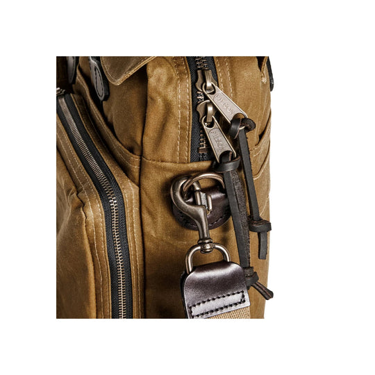 Tan canvas briefcase close-up with metal zipper pulls, leather trim, and a hanging strap clip