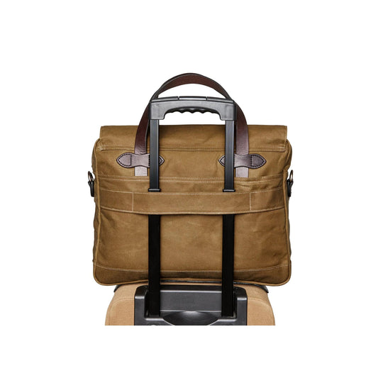 Brown waxed-canvas briefcase with leather handles and a luggage sleeve over a suitcase handle
