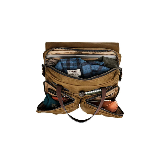 Open tan canvas briefcase with leather handles, front pockets, and a blue plaid shirt visible inside