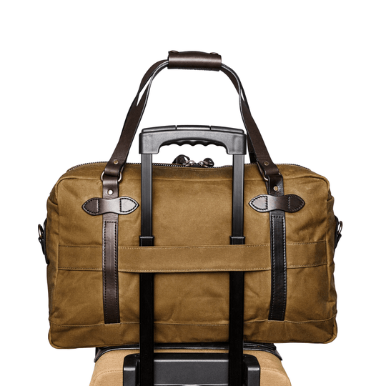 Olive-brown canvas duffle bag with dark leather straps and a telescoping handle passing through the center