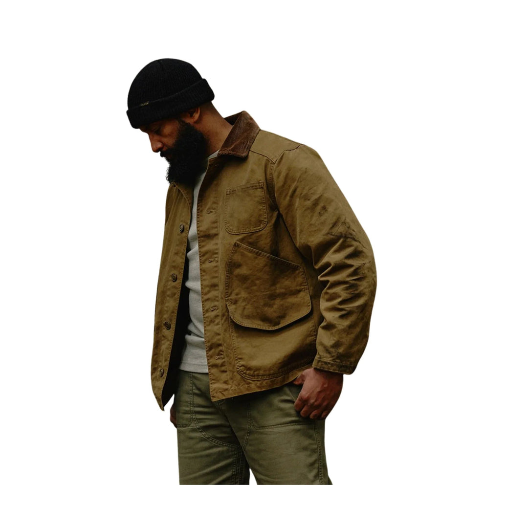 Brown canvas work jacket with large front patch pockets, worn over a gray shirt and olive pants