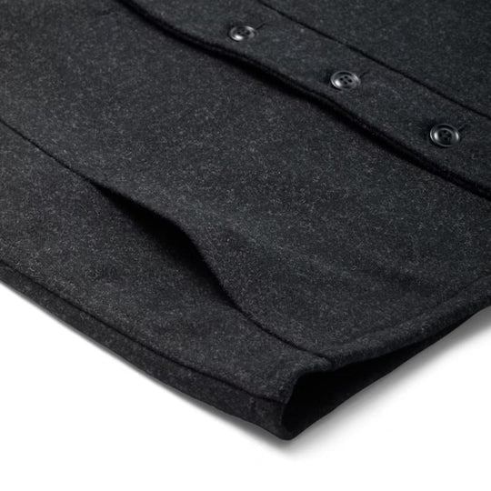 Close-up of a dark wool vest hem with button placket and stitched edges