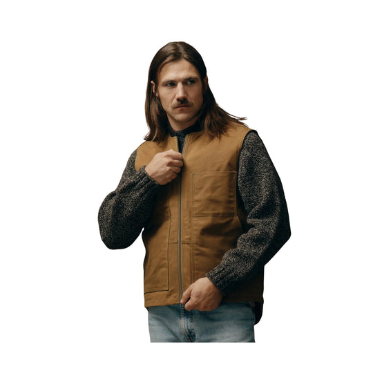 Brown canvas zip-front work vest over a dark knit sweater with jeans