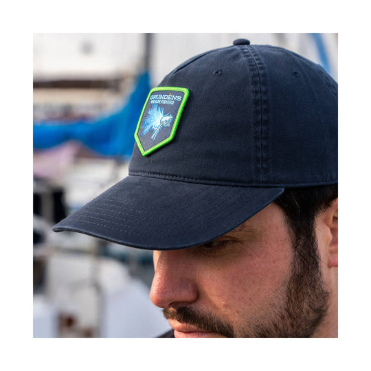 Navy baseball cap with a neon green patch showing a fish graphic and the text "GRUNDENS WE ARE FISHING"