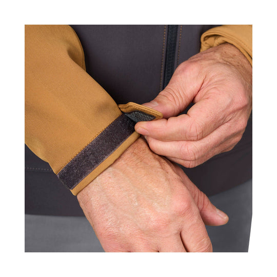 Close-up of a tan jacket sleeve with a black Velcro cuff being adjusted by hand