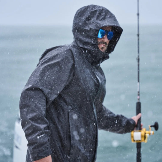 Dark hooded rain jacket worn by a person fishing in heavy rain, with mirrored blue sunglasses