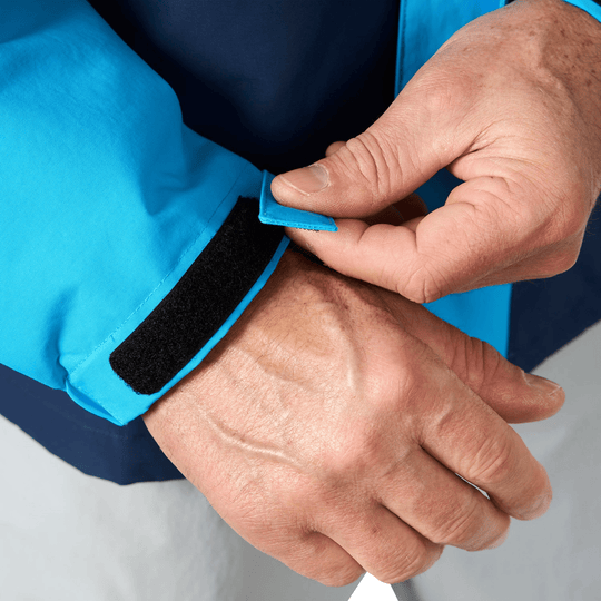 Blue jacket sleeve with adjustable Velcro wrist cuff being fastened