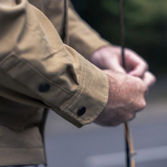 Tan button-cuff shirt jacket sleeve with hands holding a fishing rod