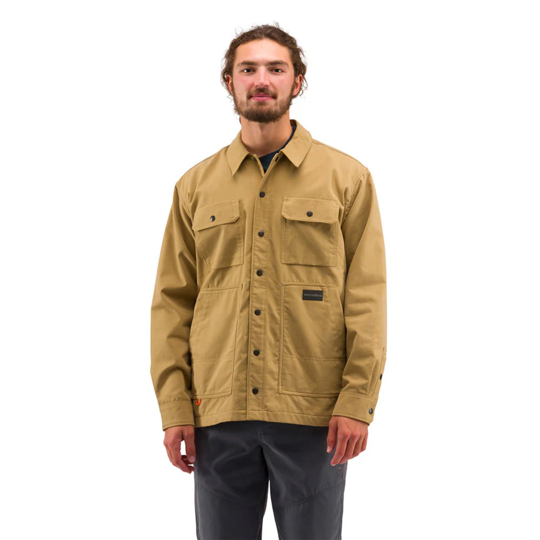 Tan button-front work jacket with chest pockets and a small logo patch, worn with dark pants