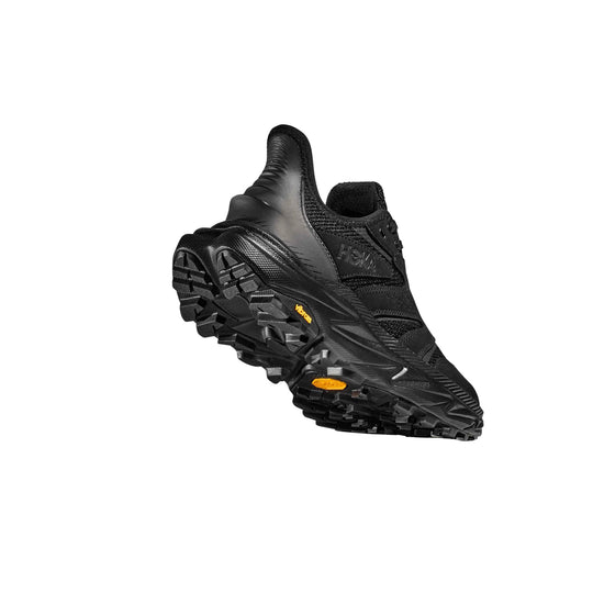 Black hiking shoe with lugged sole and yellow outsole accents, shown at an angle