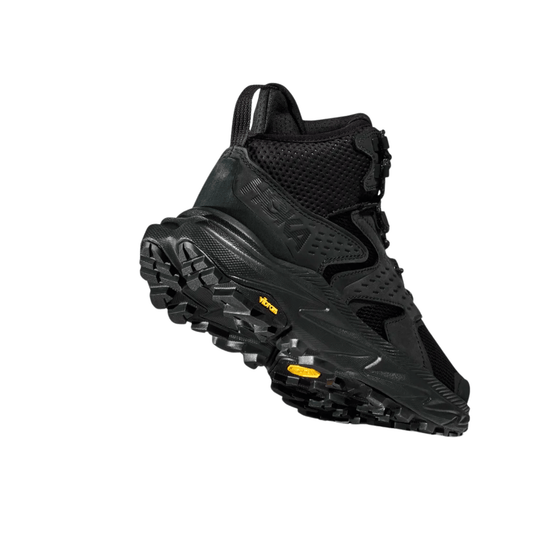 Black mid-height hiking boot with rugged lug sole, mesh panels, and a yellow Vibram label