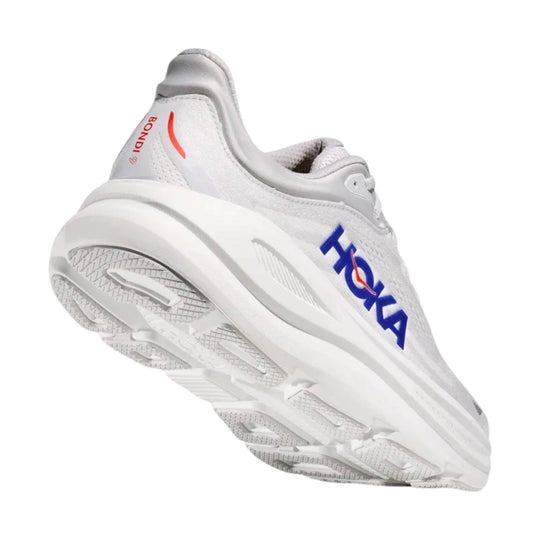 White running shoe with blue HOKA branding and orange accents, shown from the sole side.
