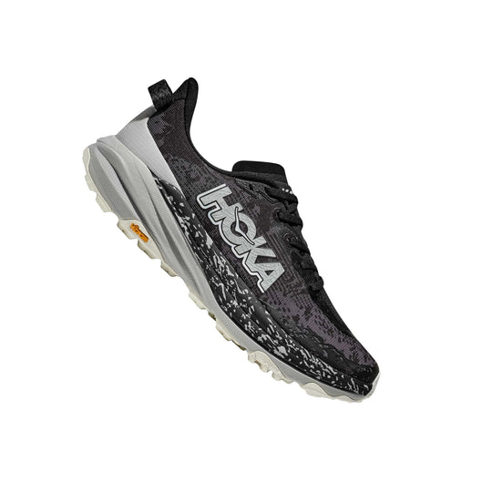 Black and gray trail running shoe with oversized side logo, white midsole, and lugged outsole