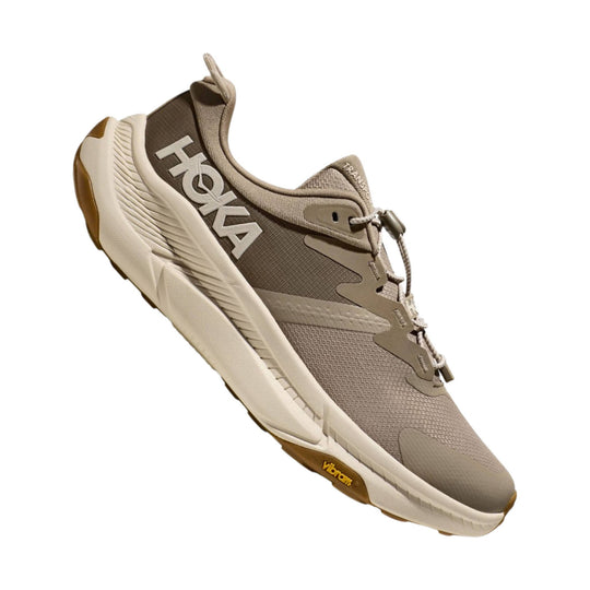Taupe and beige low-top athletic shoe with bungee laces, large side branding, and gum sole