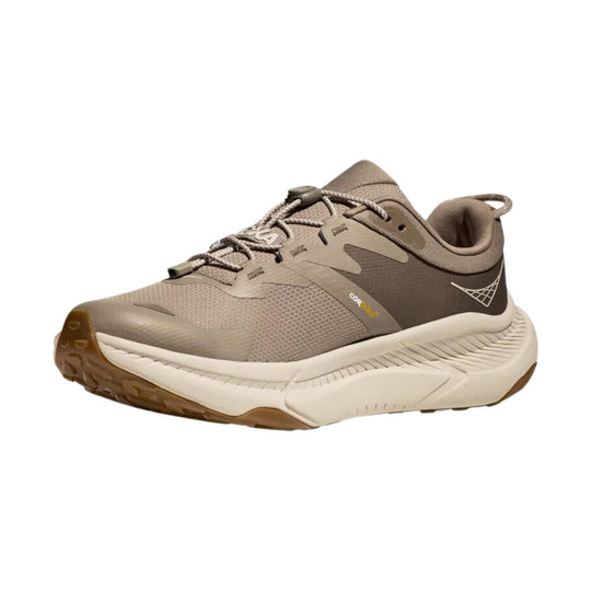 Taupe and brown athletic sneaker with a thick white sole, rope laces, and a side logo