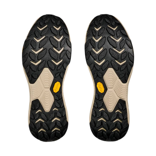 Pair of black hiking shoe outsoles with tan midfoot panels and yellow Vibram badges