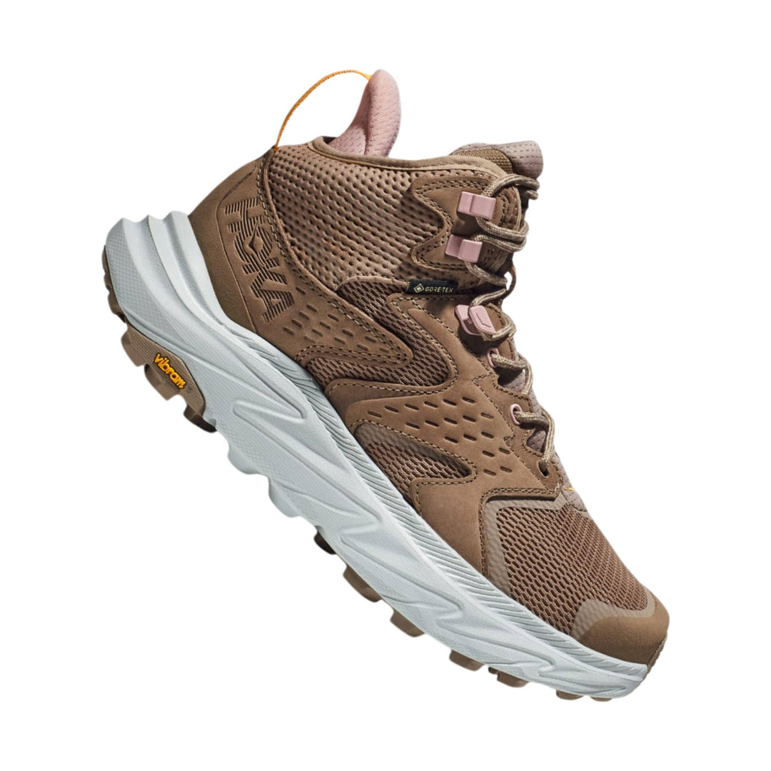 Brown mid-cut hiking boot with white sole, pink lace hooks, and treaded outsole